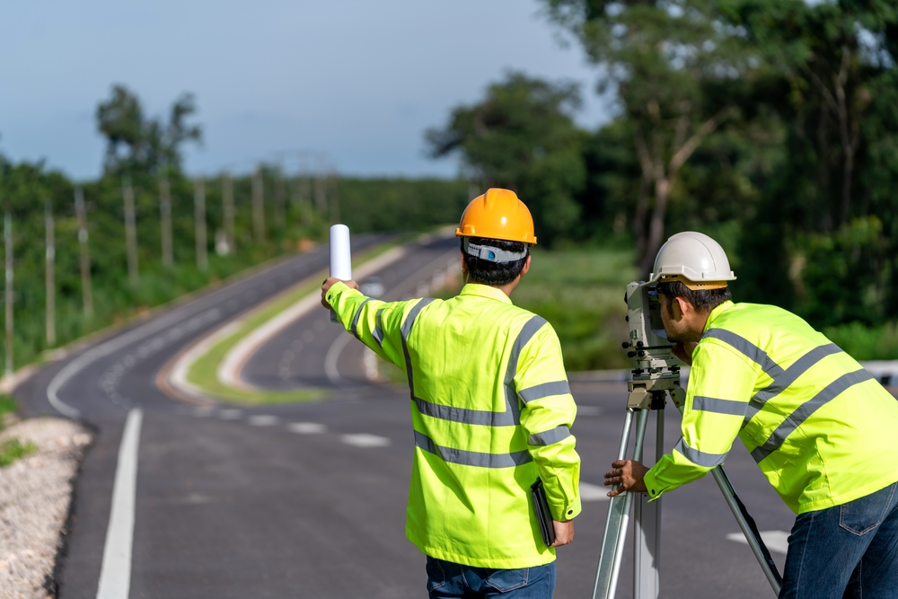 A worker applying sealant to a crack in the road surface