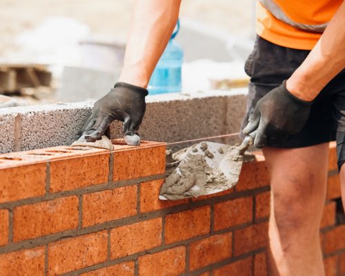 Construction,Worker,Using,Trowel,To,Lay,Brick,Wall,During,Daytime