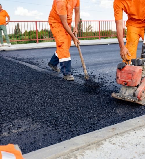 Worker,Is,Compacting,Asphalt,With,Vibrating,Compactor,Machine,,The,Other